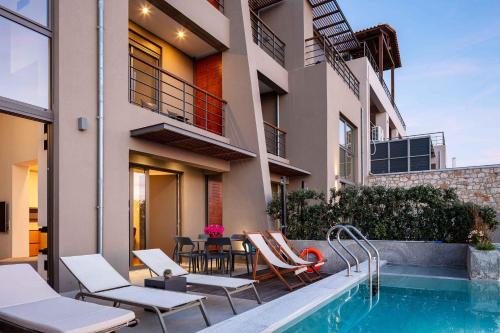 a house with a swimming pool with chairs and a table at Omnia Luxury Villas in Chania Town