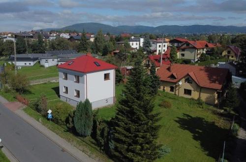 a small white house with a red roof in a city at Apartament u Jędrusia in Żywiec