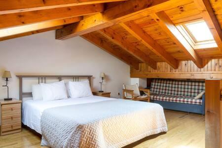 アルプにあるla Cabana dels Isardsの白いベッドと木製の天井が備わるベッドルーム1室が備わります。