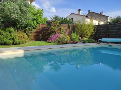 a swimming pool with blue water in a yard at Chambre direct piscine in Talence