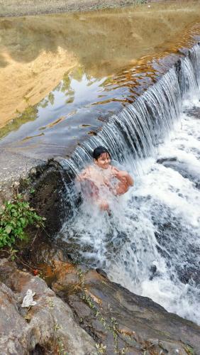 a man is swimming in a waterfall at Adaara Retreat - Pet Friendly Cottages, Almora in Almora