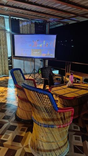 a room with chairs and a screen with a presentation at Adaara Retreat - Pet Friendly Cottages, Almora in Almora
