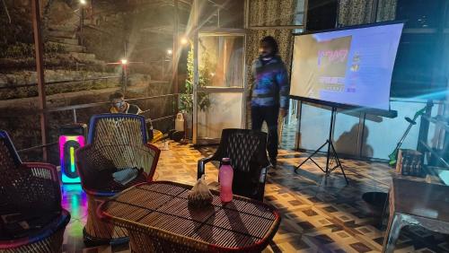a person standing on a screen in a room with a table at Adaara Retreat - Pet Friendly Cottages, Almora in Almora