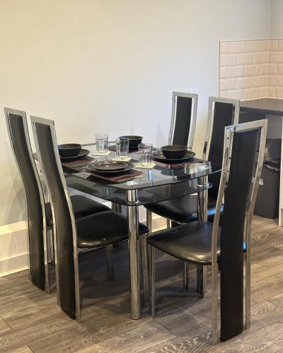 einen Esstisch mit schwarzen Stühlen und einen schwarzen Tisch mit Gläsern in der Unterkunft The Luxe By Elegant Aparts in Bradford