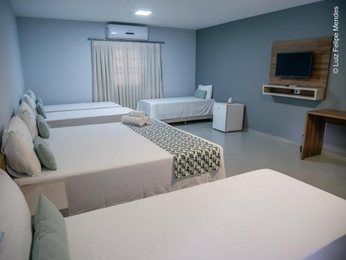 a hotel room with two beds and a tv at HOTEL AGUAS DE BODOQUENA in Bodoquena
