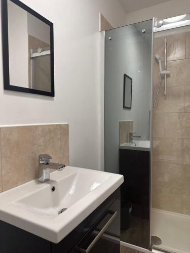 ein Badezimmer mit einem weißen Waschbecken und einer Dusche in der Unterkunft The Luxe By Elegant Aparts in Bradford