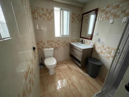 a bathroom with a toilet and a sink and a mirror at Luminoso piso cerca de la playa in Cullera