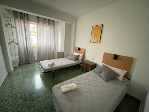 a hotel room with two beds and a window at Luminoso piso cerca de la playa in Cullera