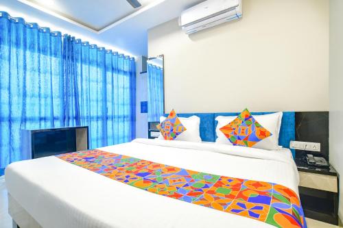 1 dormitorio con 1 cama grande y cortinas azules en FabHotel Lake View III en Indore