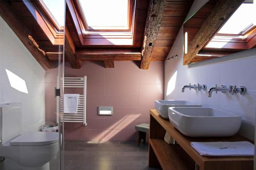 a bathroom with two sinks and a toilet and skylights at Emebed Posada in Castrojeriz