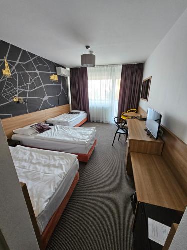 a hotel room with two beds and a desk at Hotel Bratislava in Bratislava