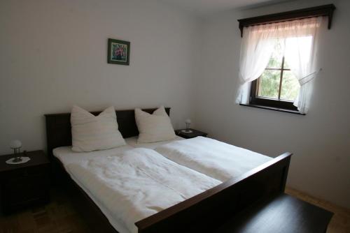 1 dormitorio con 1 cama con sábanas blancas y ventana en Farm Stay Frank Ozmec Wine and Glamping estate, en Ljutomer