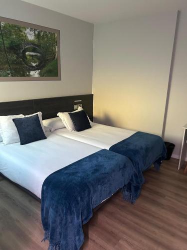 a large bed with a blue blanket on top of it at Pension San Anton in Melide