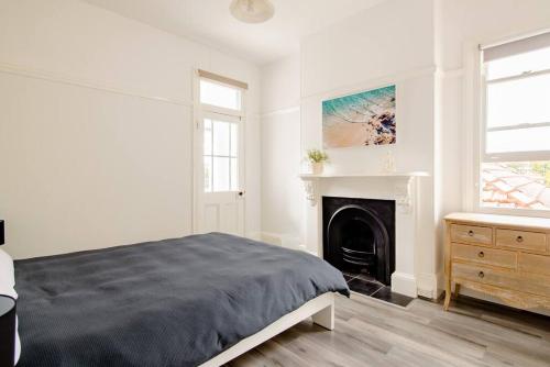 Dormitorio blanco con cama y chimenea en Beautiful & Ultra Convenient 4-bdrm Terrace en Sídney
