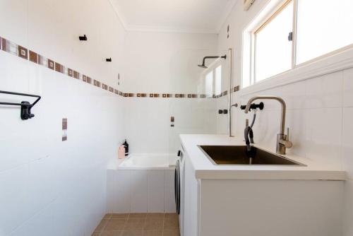 cocina blanca con fregadero y ventana en Beautiful & Ultra Convenient 4-bdrm Terrace en Sídney