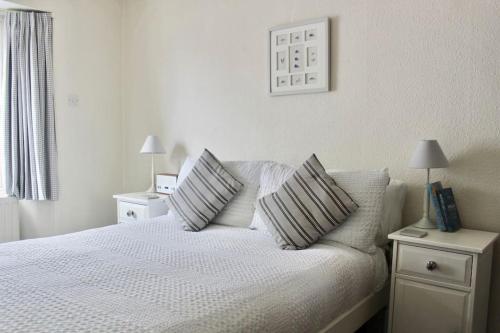 a bedroom with a white bed with pillows on it at Holiday Cottage with Seafront Beach Hut, Lyme Regis, Dorset in Lyme Regis