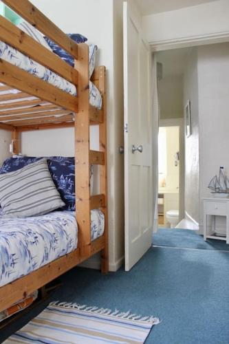 a bedroom with two bunk beds and a hallway at Holiday Cottage with Beach Hut, Lyme Regis, Dorset in Lyme Regis