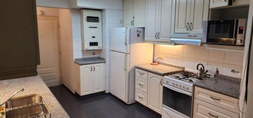 una cocina con electrodomésticos blancos y armarios blancos en Nueva Cordoba en Córdoba