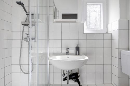 biała łazienka z umywalką i prysznicem w obiekcie Bei der alten Keksfabrik w mieście Hamburg