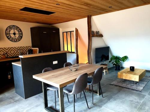 une table à manger et des chaises dans une pièce avec une horloge dans l'établissement Superbe T3 Neuf avec terrasse + vue montagne, à Briançon