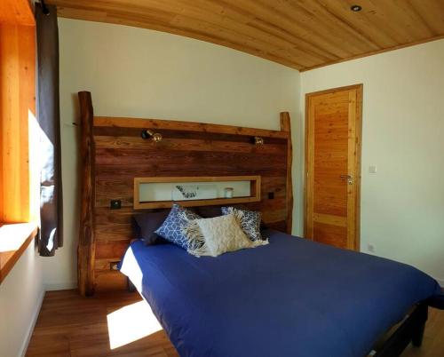 - une chambre avec un lit bleu et une tête de lit en bois dans l'établissement Superbe T3 Neuf avec terrasse + vue montagne, à Briançon