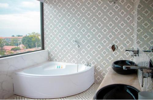 a white tub in a bathroom with a window at Lake view property in Kisubi