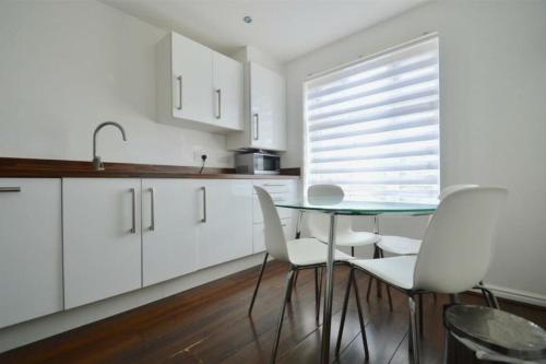 a kitchen with a glass table and white cabinets at 3 Bedroom House in Kent by AV Stays in Sittingbourne