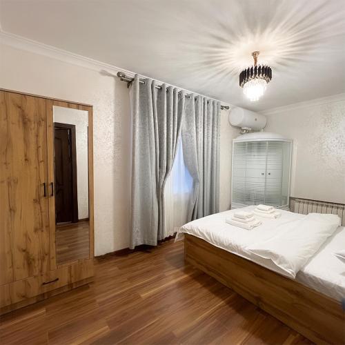 een slaapkamer met een bed en een kroonluchter bij Cozy Hostel in Yunusobod