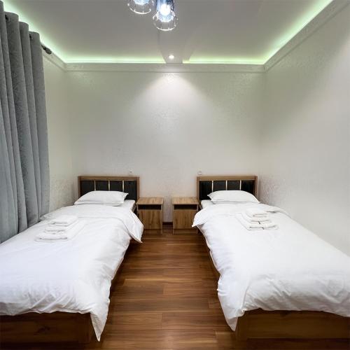 two beds in a room with white sheets at Cozy Hostel in Yunusobod