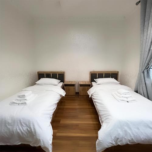 two beds in a room with white sheets at Cozy Hostel in Yunusobod