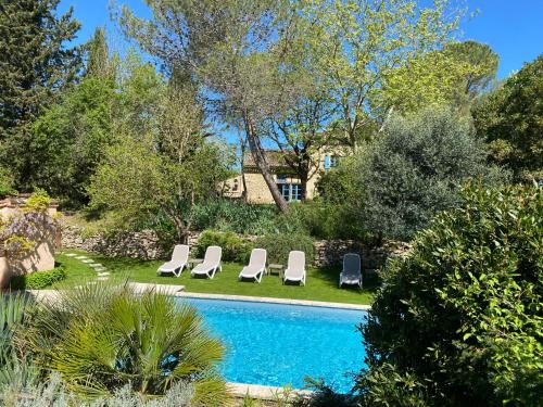 a swimming pool with lounge chairs and a house at Le Clos Pastel in Virac