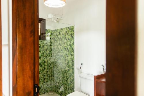 a bathroom with a toilet and a shower with green tiles at Casa Bella Barra Beach in Barra Grande
