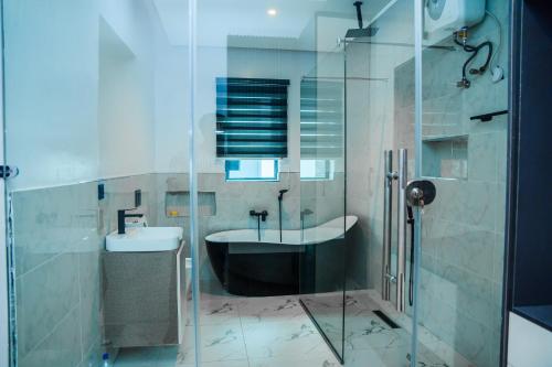 a bathroom with a shower and a tub and a sink at Elim Maisonette in Lekki