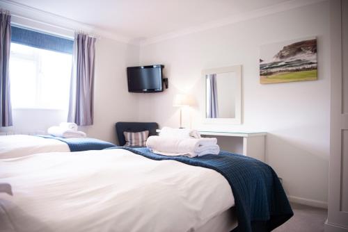 a hotel room with two beds and a tv on the wall at Trevose Golf and Country Club in Padstow