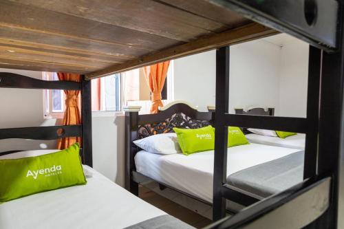 2 Etagenbetten in einem Zimmer mit grünen Kissen in der Unterkunft Hotel Bacatá in Bucaramanga