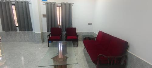 a waiting room with red chairs and a glass table at Dev Kirtan Villa in Daman