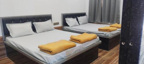 two beds with yellow pillows on them in a room at Dev Kirtan Villa in Daman