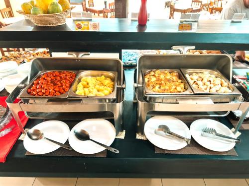 a buffet with two trays of food on white plates at Hotel Fênix in Porto Seguro