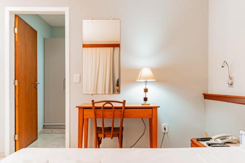 a bedroom with a desk with a chair and a mirror at Champagnat Praia Hotel in Vila Velha