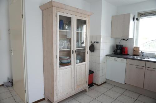 a kitchen with a wooden cabinet with dishes in it at Kustverhuur, Breskens Zwin 077 in Breskens