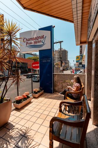 a woman sitting in a chair next to a park truck sign at Champagnat Praia Hotel in Vila Velha