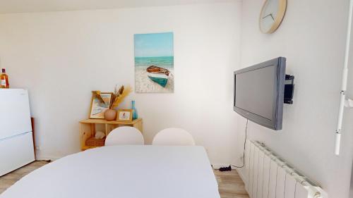 Cette chambre blanche dispose d'une télévision et d'un lit. dans l'établissement Le Bateau Ivre 50 m de la Plage, à Saint-Gilles-Croix-de-Vie
