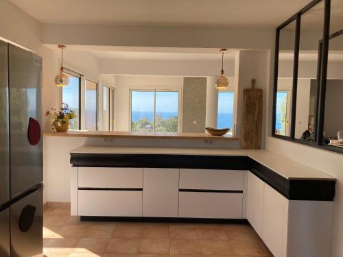 eine Küche mit weißen Schränken und einem Spiegel in der Unterkunft Villa La Ronde des Soleils in Coti-Chiavari