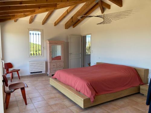 ein Schlafzimmer mit einem roten Bett und einem Stuhl in der Unterkunft Villa La Ronde des Soleils in Coti-Chiavari