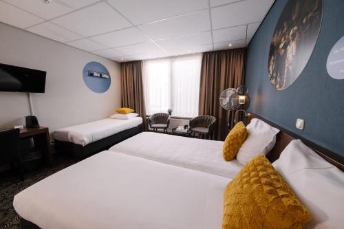 a hotel room with two beds and a desk at Hotel de Koophandel in Delft