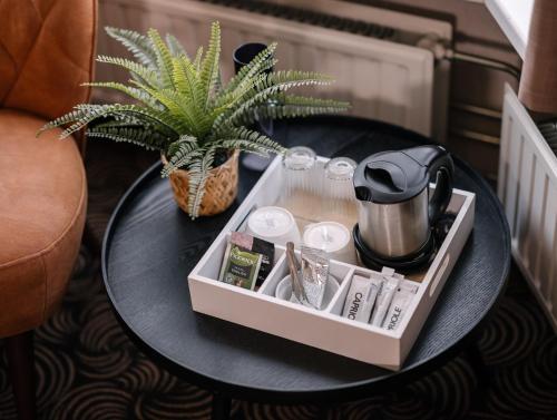 a tray on a table with a tea pot and a plant at Hotel de Koophandel in Delft