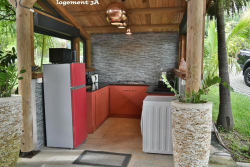 an outdoor kitchen with a red refrigerator and a brick wall at Loc974 Les Cocotiers in Saint-Leu