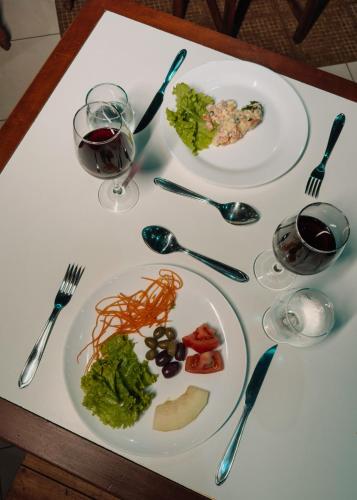 a table with plates of food and glasses of wine at Hotel Fênix in Porto Seguro