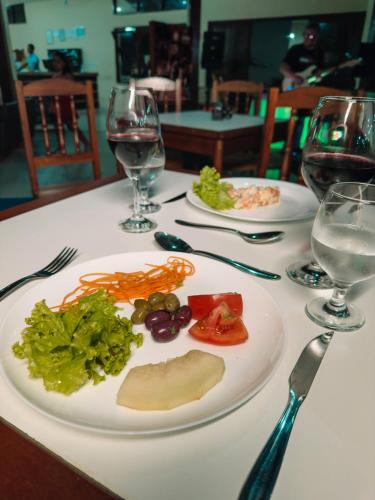 a plate of food on a table with wine glasses at Hotel Fênix in Porto Seguro