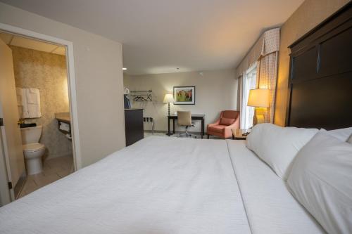 a bedroom with a large white bed and a bathroom at Peek'n Peak Resort Trademark Collection by Wyndham in Clymer